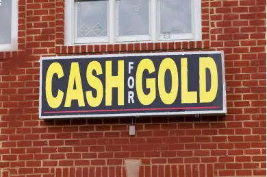 A Cash for Gold shop sign mounted on a brick wall